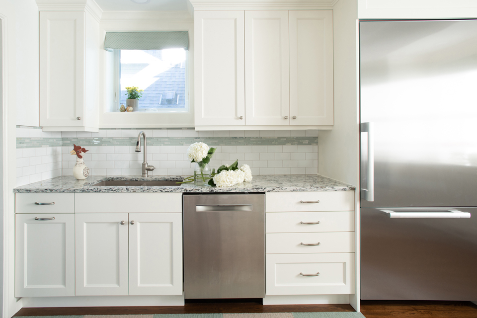 Fresh farmhouse kitchen with white cabinets and tile backsplash 